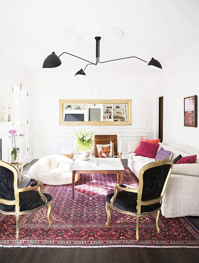 Bold living room with a red and magenta palette, grounded by black and gold fauteuils.