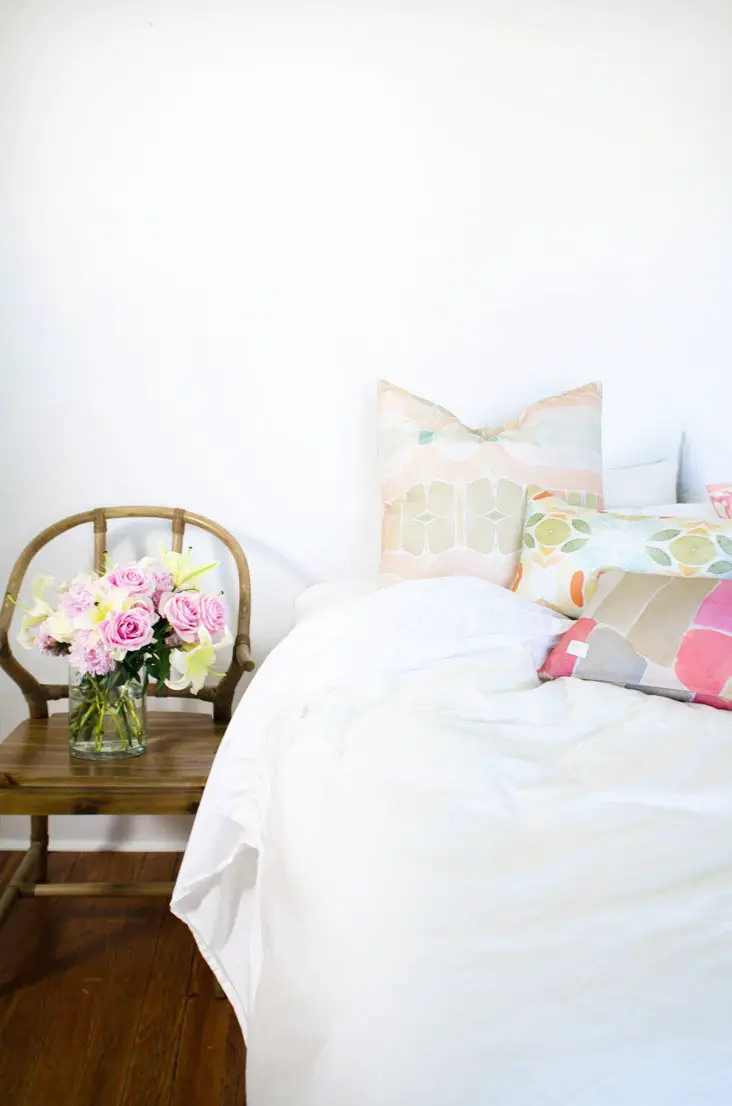White bedroom with splashes of colorful watercolor patterns from bunglo's pillow collection.