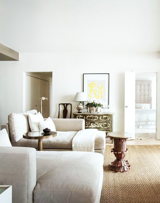 Serene living space with white walls,  linen daybeds, and antique accents in the pied-à-terre of architect Bill Ingram.