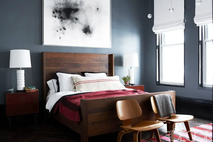 A dark moody bedroom with charcoal walls and red accents.