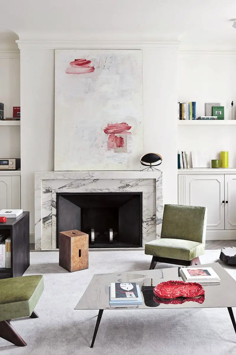 Marble fireplace, modern art, and green chairs in a Paris apartment.