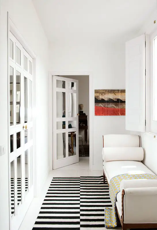 Hallway with graphic rug, chaise and mirrored doors via @thouswellblog