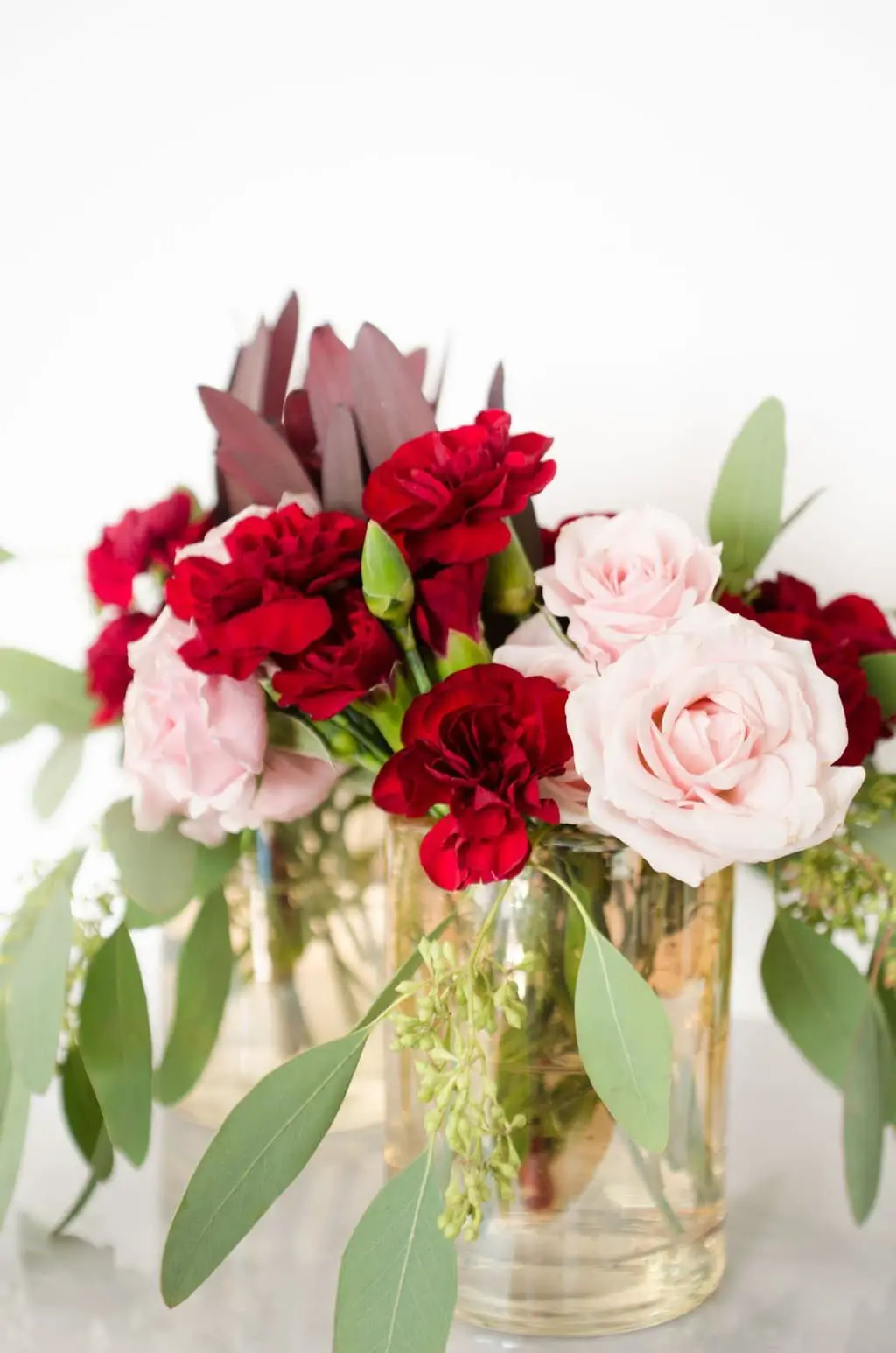 Pink roses, red carnations, leucadendron, and seeded eucalyptus via @thouswellblog