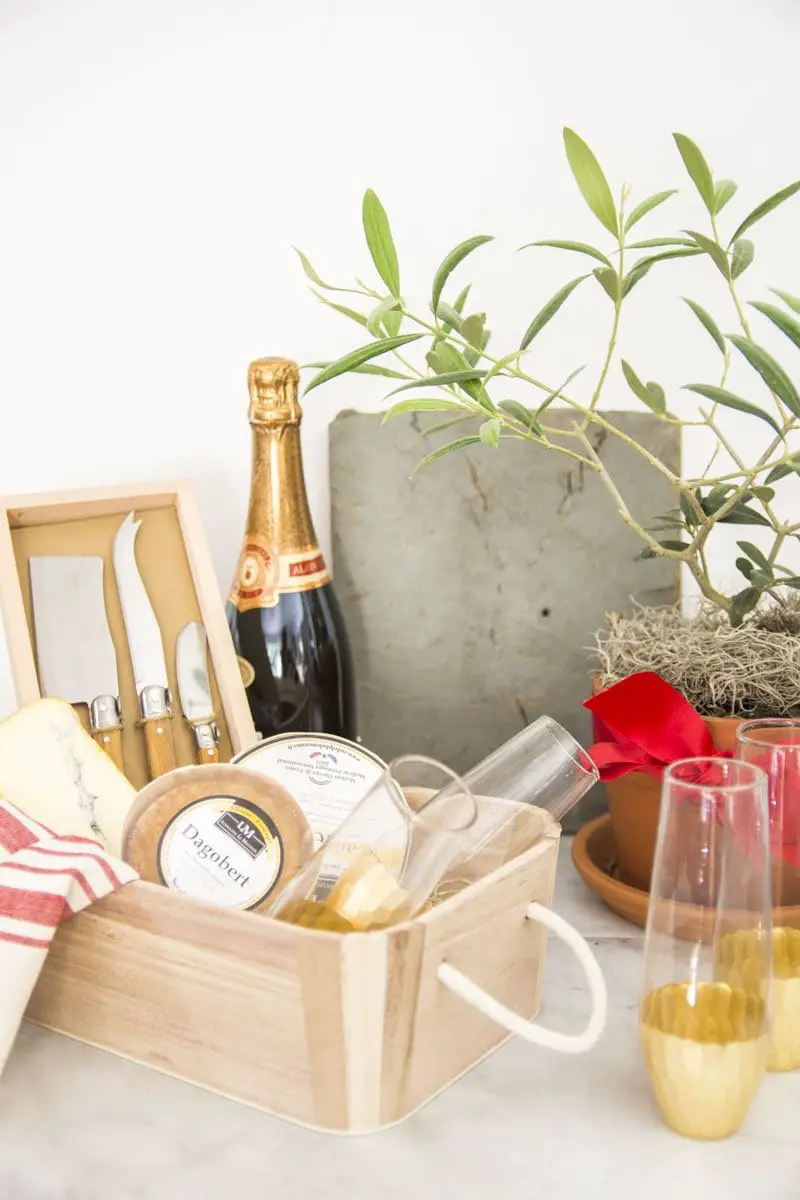 Gift basket with cheese, knives, tea towel, and champagne flutes from World Market on Thou Swell