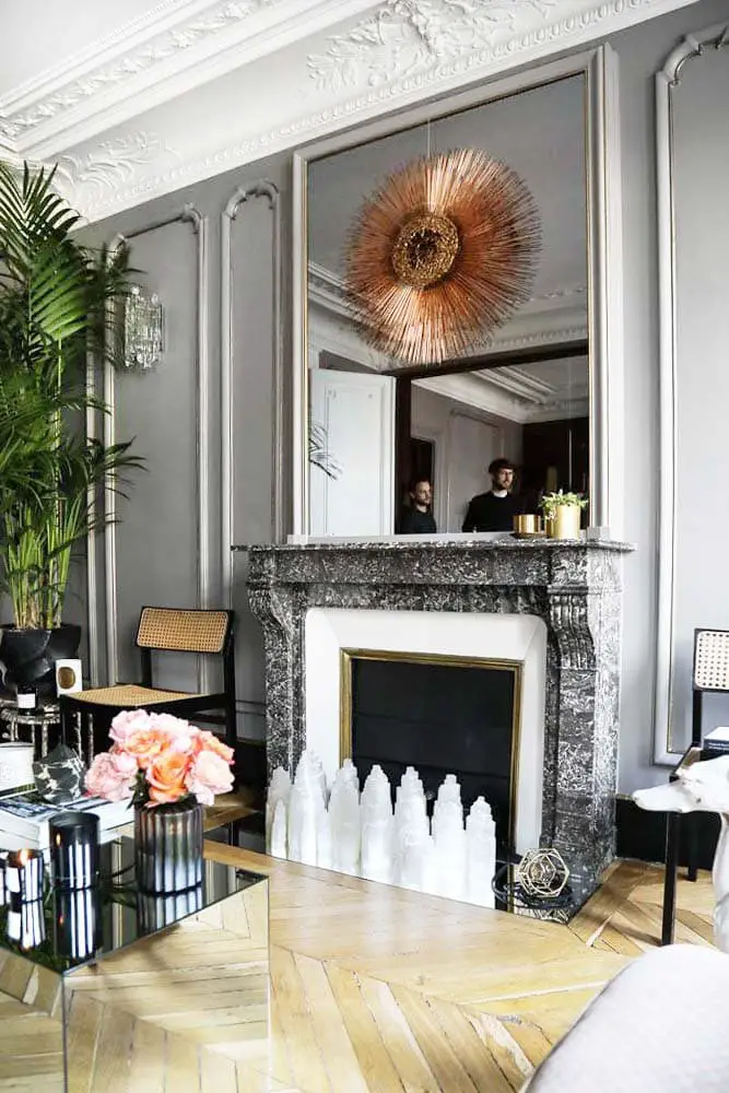 Grey living room in Paris pied-à-terre with sunburst mirror and chevron flooring on Thou Swell @thouswellblog #grey #greyroom #greypaint #greywalls #frenchdesign #apartmentdesign #luxurydesign #interiordesign #paris #parishome