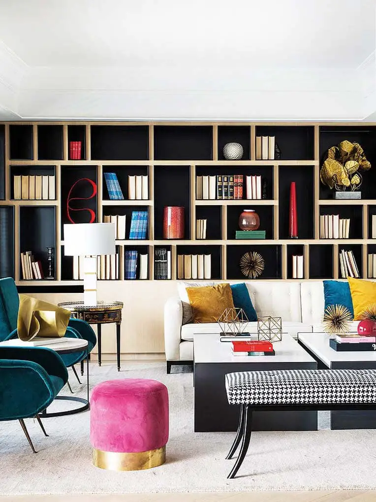 Colorful modern living room with pink ottoman and built-in bookshelves on Thou Swell @thouswellblog