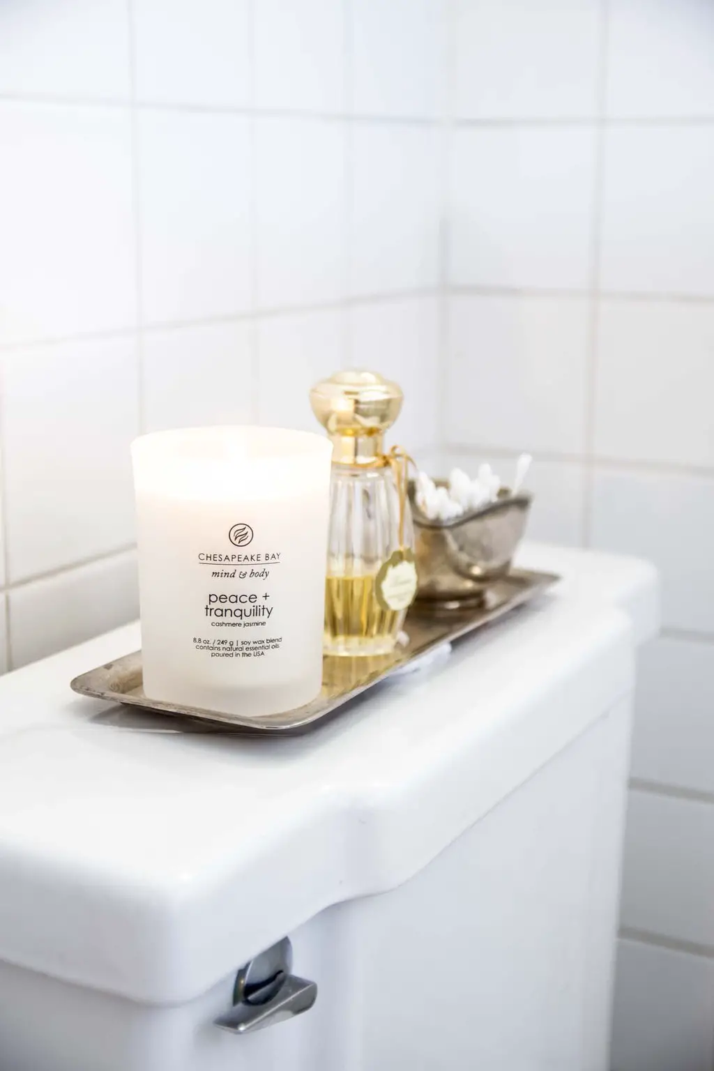 Peace & Tranquility scented candle in white bathroom with silver tray and perfume on Thou Swell @thouswellblog
