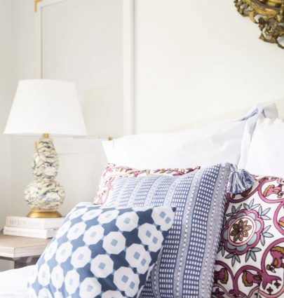 Colorful patterned throw pillows on the bed in a simple white bedroom on Thou Swell @thouswellblog
