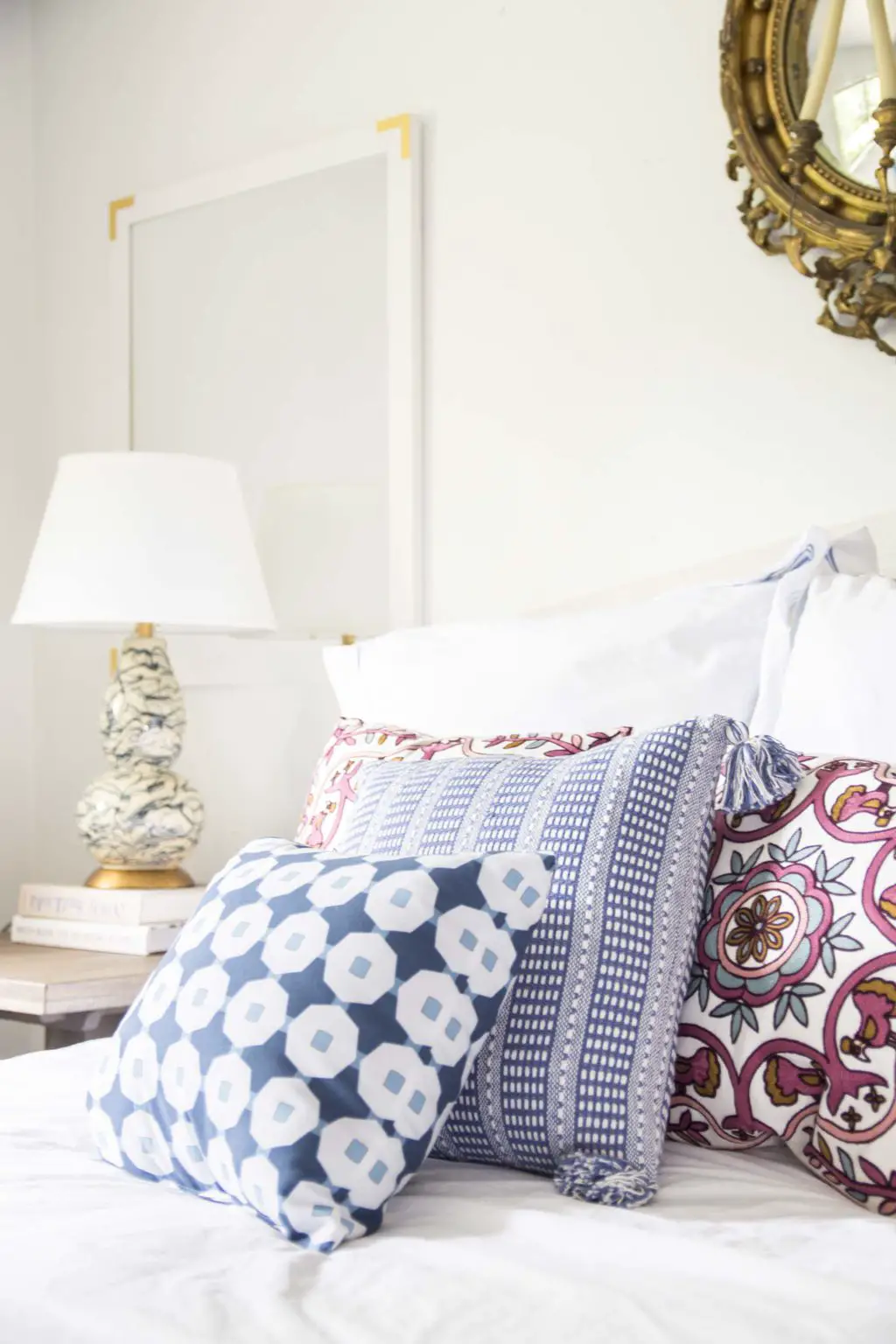 Colorful patterned throw pillows on the bed in a simple white bedroom on Thou Swell @thouswellblog