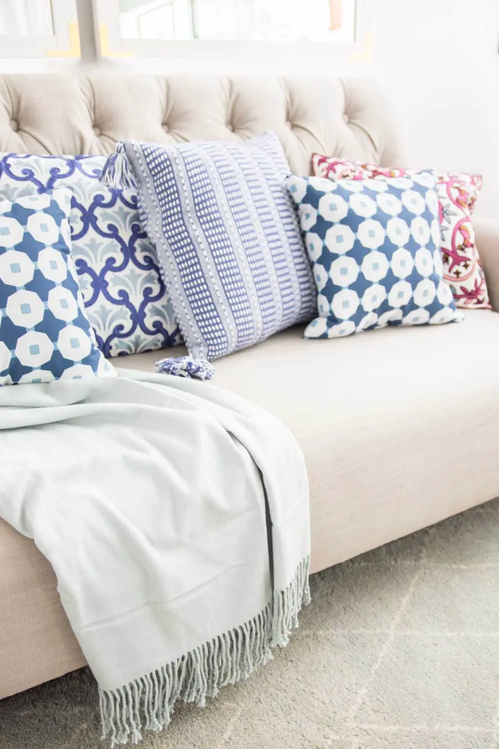 Colorful patterned throw pillows on a tufted sofa in the living room on Thou Swell @thouswellblog