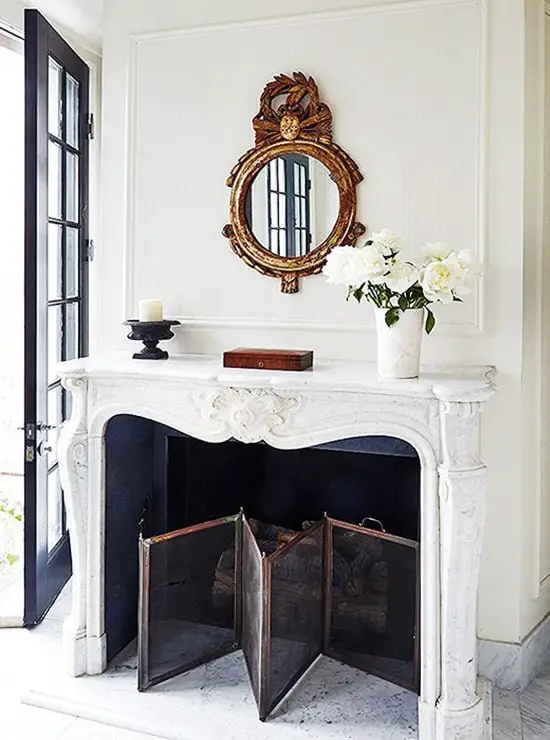 Marble fireplace mantel with gold leaf bullseye mirror and folding fireplace screen on Thou Swell @thouswellblog