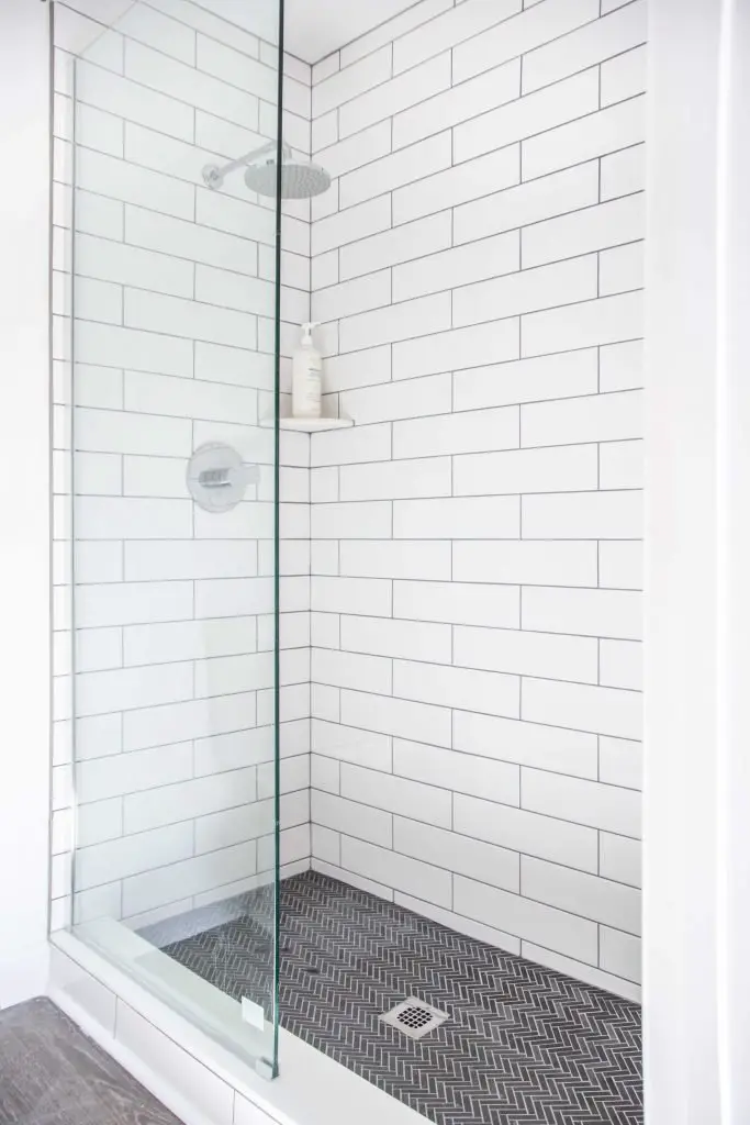Master bathroom shower tile renovation with grey herringbone mosaic and white subway tile on Thou Swell #bathroom #masterbathroom #showertile #subwaytile #herringbonetile #walkinshower #shower