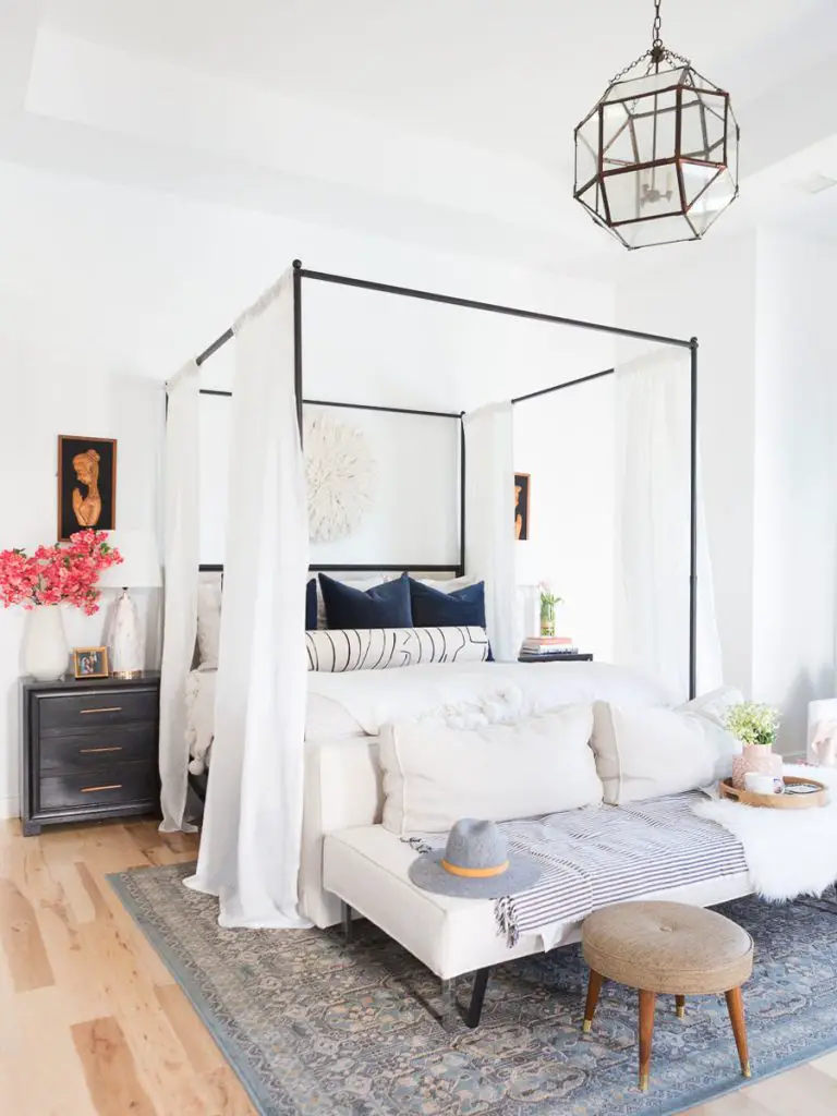 Bright and playful master bedroom design with canopy bed, white curtains, upholstered bench, and grey area rug on Thou Swell @thouswellblog #bedroom #bedroomdesign #masterbedroom #bedroomdecor #jujuhat #interiordesign