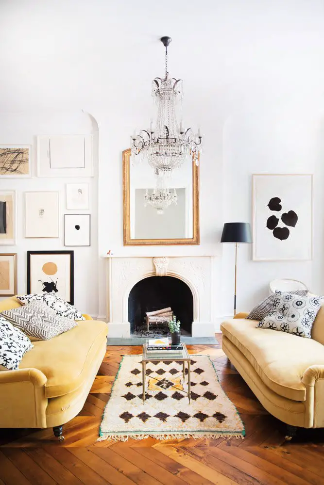 Glamorous neutrals in a West Village townhouse living room with mustard yellow velvet sofas, crystal chandelier, Moroccan rug, and gallery wall on Thou Swell #westvillage #livingroom #yellowsofa #velvetsofa #gallerywall #livingroomdesign #interiordesign #homedesign