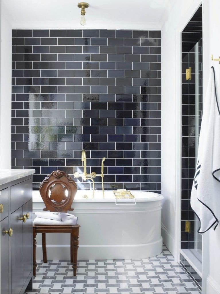 Black and white custom bathroom subway tile backsplash with antique chair and standing bathtub in Tudor house in Atlanta on Thou Swell @thouswellblog #tudor #tudorhouse #renovation #historichouse #historichome #atlantahome #atlantahomes #interiordesign #traditionaldesign #vintagedesign #bathroom #bathroomdesign #subwaytile