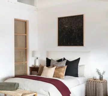 California bedroom design with black painting above bed and vintage kilim textiles and pouf designed by Amber Interiors on Thou Swell #bedroom #bedroomdesign #bedroomdecor #homedecor #homedecorideas #interiordesign