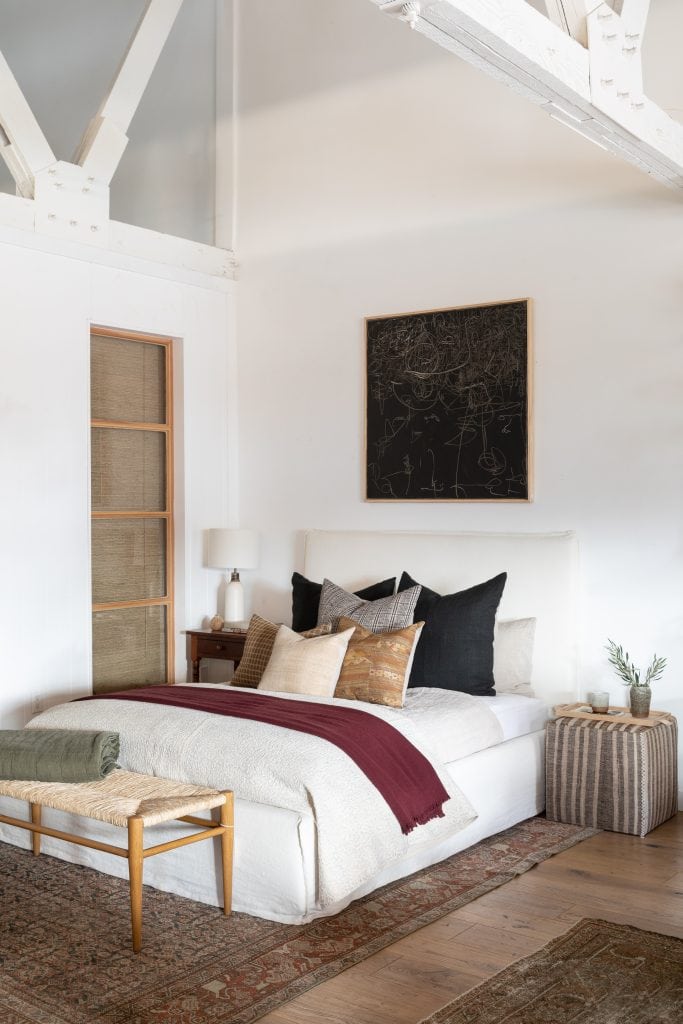 California bedroom design with black painting above bed and vintage kilim textiles and pouf designed by Amber Interiors on Thou Swell #bedroom #bedroomdesign #bedroomdecor #homedecor #homedecorideas #interiordesign