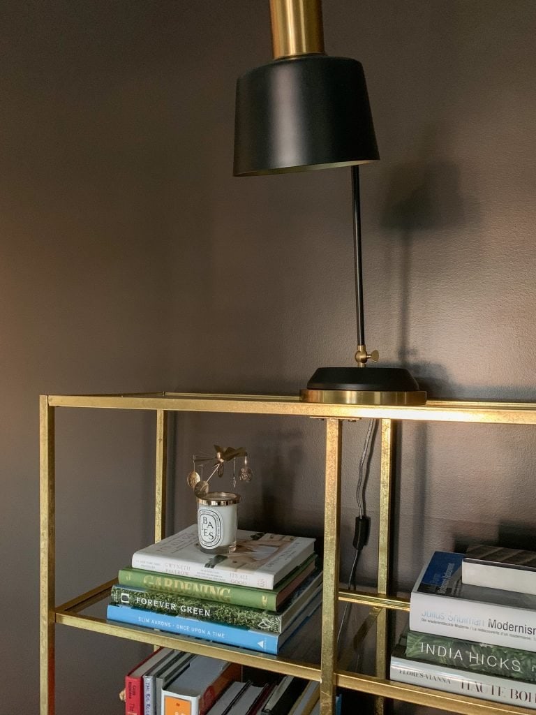 Brown study living room design with gold bookcase, black lamp, and brown walls on Thou Swell #study #livingroom #bookcase #tasklamp #blacklamp #goldbookcase #brownwalls