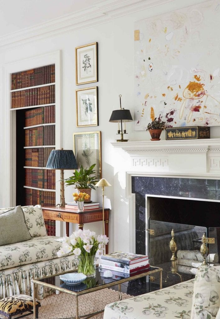 Secret bookcase door in traditional living room by Caroline Gidiere in Mountain Brook with fireplace mantel and abstract painting on Thou Swell #secretdoor #livingroom #livingroomdesign #fireplace #fireplacemantel #mantel #bookcasedoor #librarydoor 