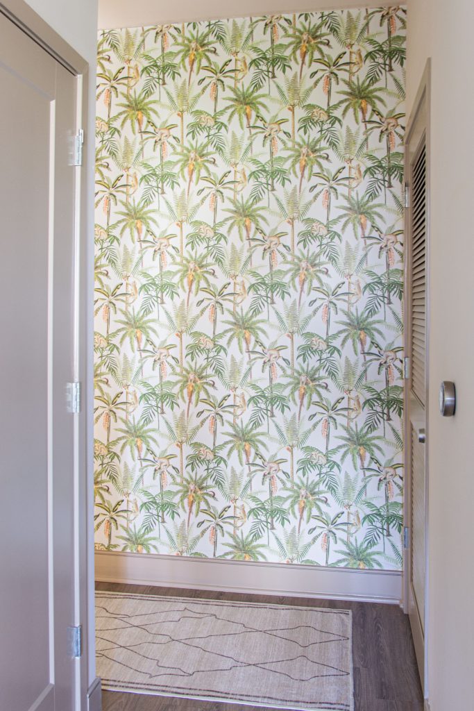 Tropical leaf and monkey wallpaper by Walls Republic in an apartment entryway accent wall on Thou Swell #homedecor #homedecorideas #wallpaper #tropicalwallpaper #monkeys #accentwall #wallsrepublic