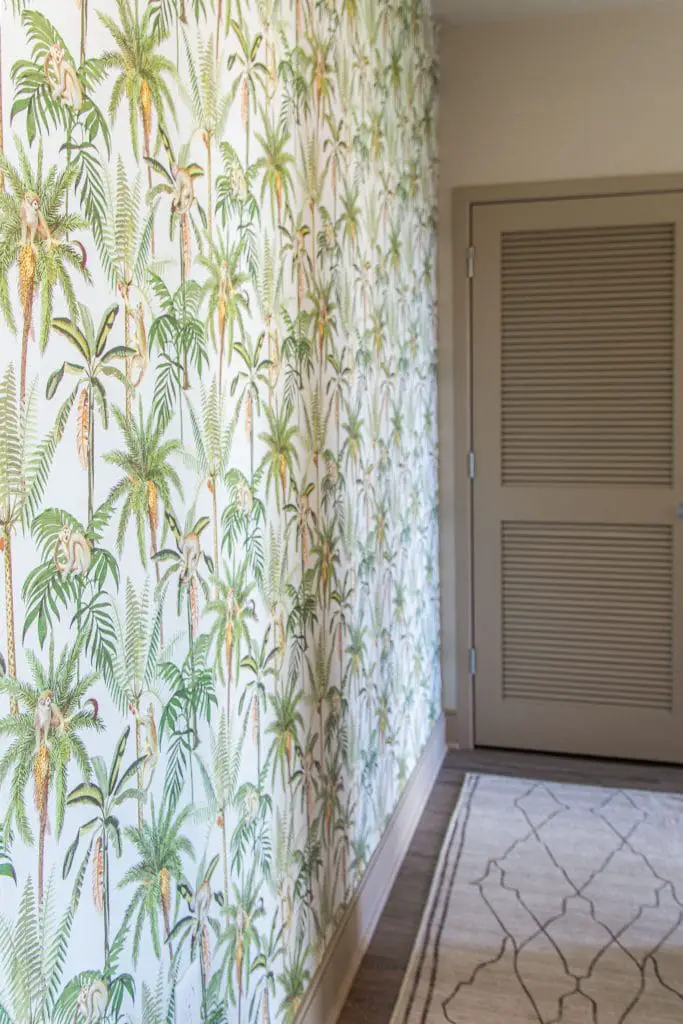 Tropical leaf and monkey wallpaper by Walls Republic in an apartment entryway accent wall on Thou Swell #homedecor #homedecorideas #wallpaper #tropicalwallpaper #monkeys #accentwall #wallsrepublic