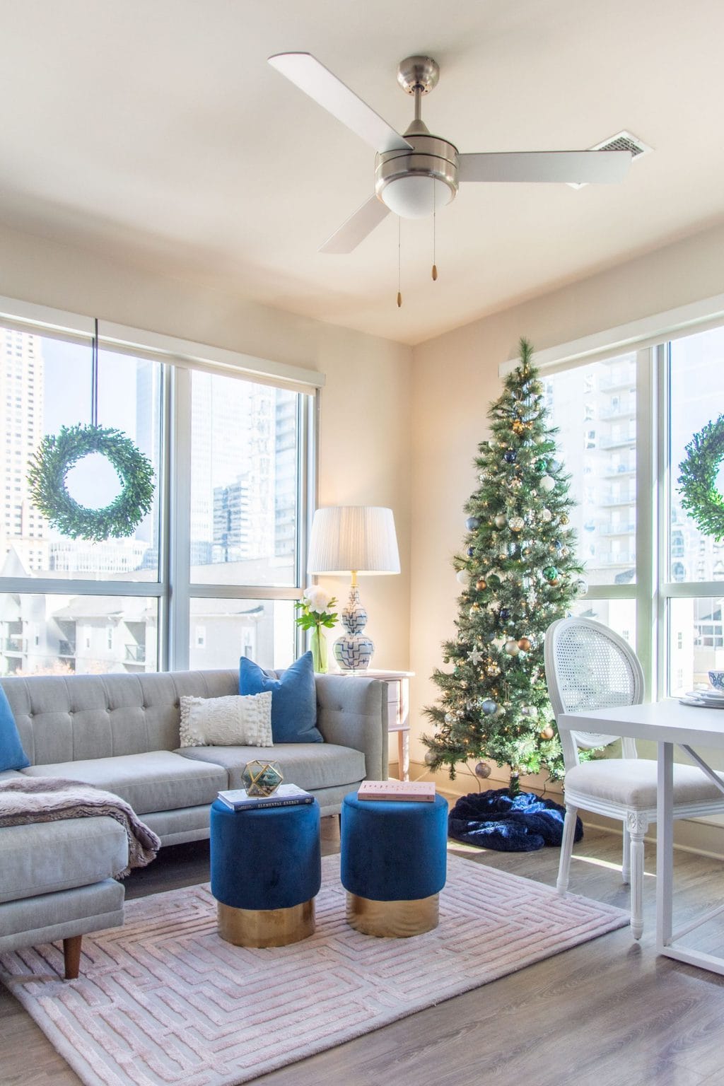 Apartment living room Christmas tree holiday decor with pink and blue, maze rug, velvet stools, and tan sectional by Kevin O'Gara on Thou Swell #apartmentstyle #apartmentdesign #apartmentdecor #livingroom #livingroomdesign #livingroomdecor #christmastree #holidaydecor #christmastyle #homedecorideas