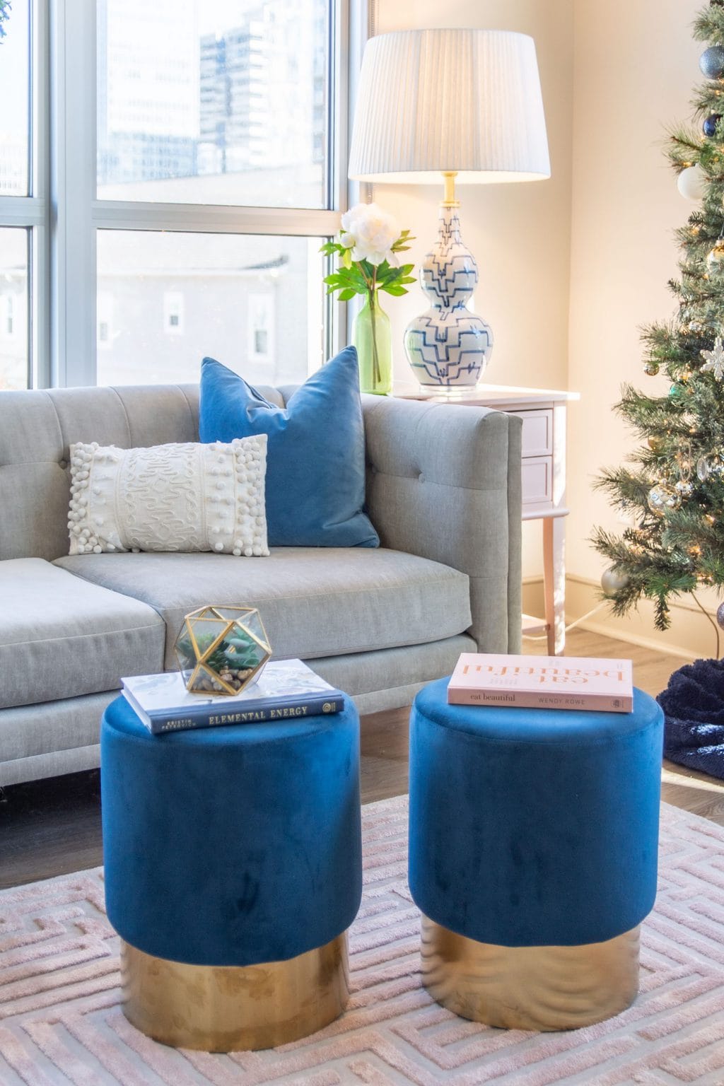 Apartment living room Christmas tree holiday decor with pink and blue, maze rug, velvet stools, and tan sectional by Kevin O'Gara on Thou Swell #apartmentstyle #apartmentdesign #apartmentdecor #livingroom #livingroomdesign #livingroomdecor #christmastree #holidaydecor #christmastyle #homedecorideas