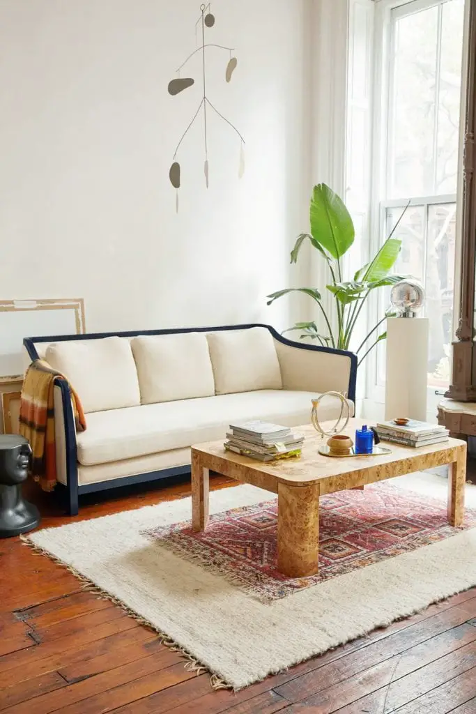 Pied-a-terre furniture collection by Urban Outfitters home with cream and black frame sofa with burl coffee table on Thou Swell 