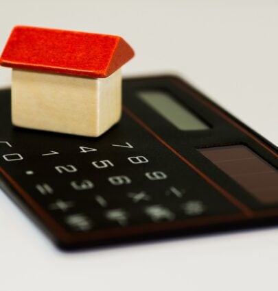 a wooden block house on top of a calculator
