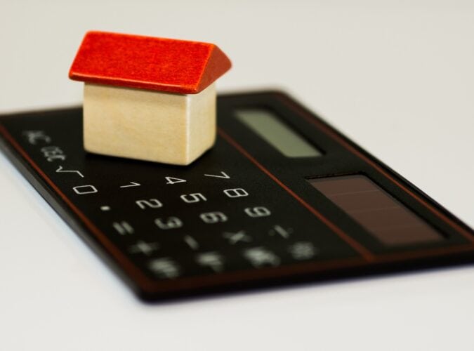 a wooden block house on top of a calculator